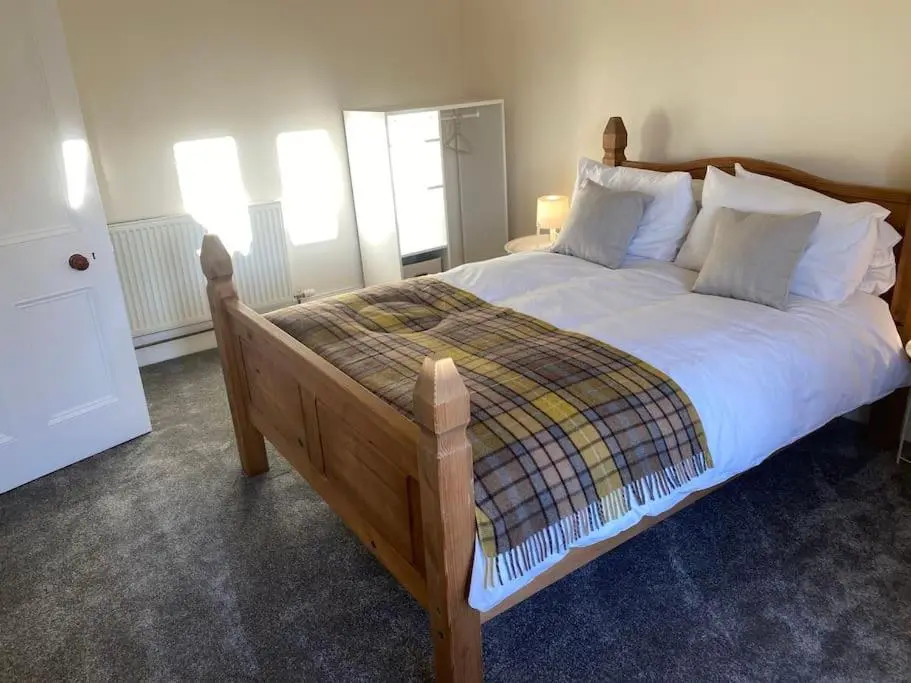 a bedroom with a large bed with white sheets and pillows at Heather House, beautiful family home, sleeps 8 in Inverness
