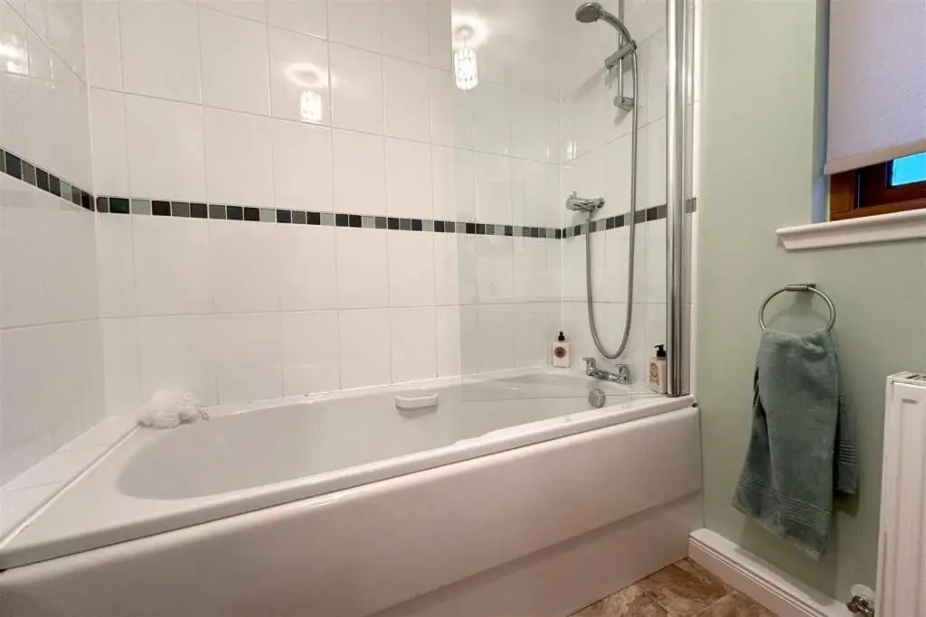 a white bathroom with a tub and a shower at The Old Mill Apartment, on NC500 in Brora