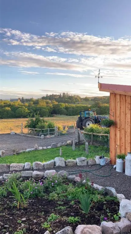 a tractor parked in a field with a garden at Migdale Pods Luxury Glamping in Bonar Bridge