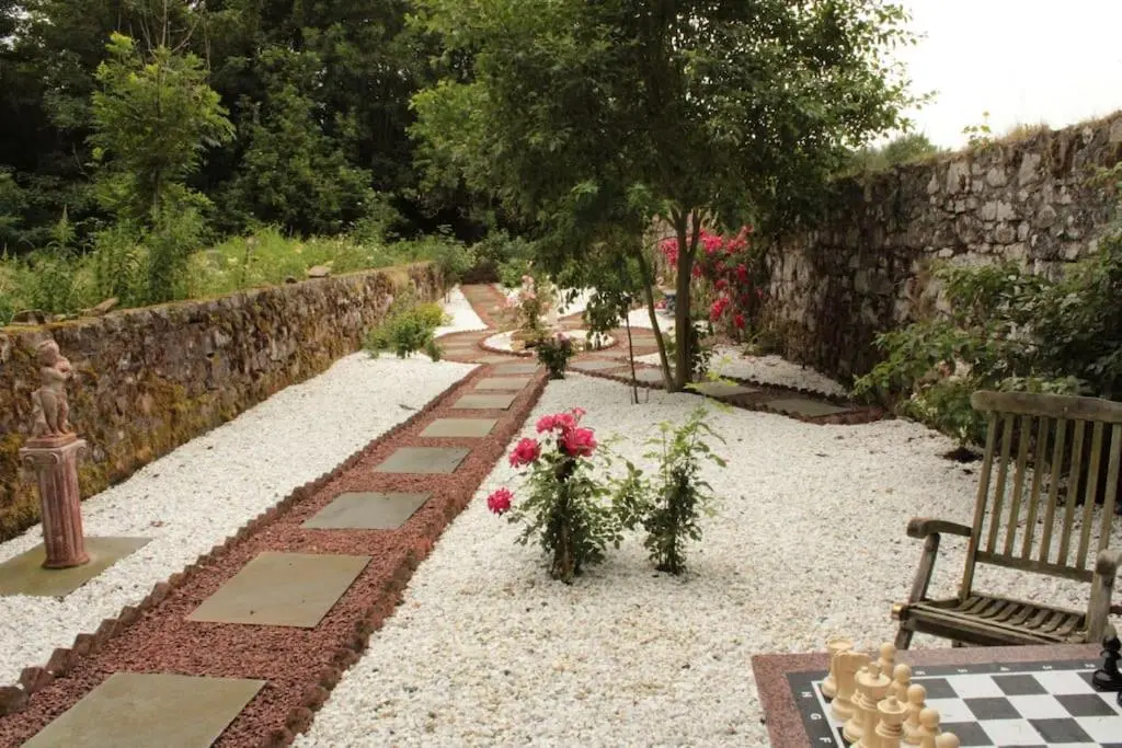a garden with a bench and flowers and a stone wall at Spacious Cottage in the Grounds of a Scottish Castle in Insch