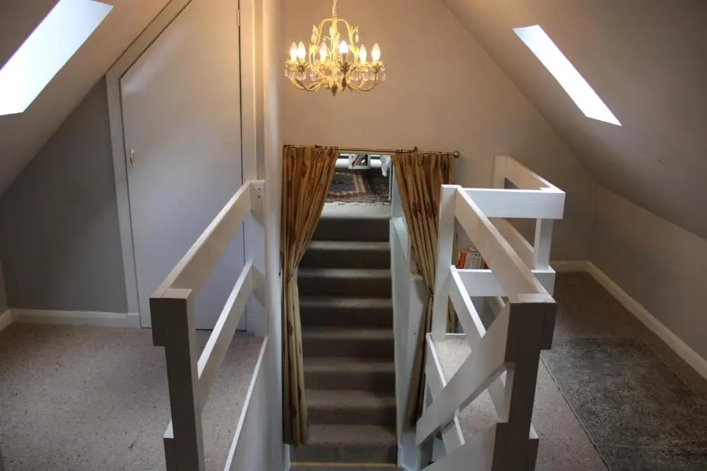 a staircase in a house with a chandelier at Spacious Cottage in the Grounds of a Scottish Castle in Insch