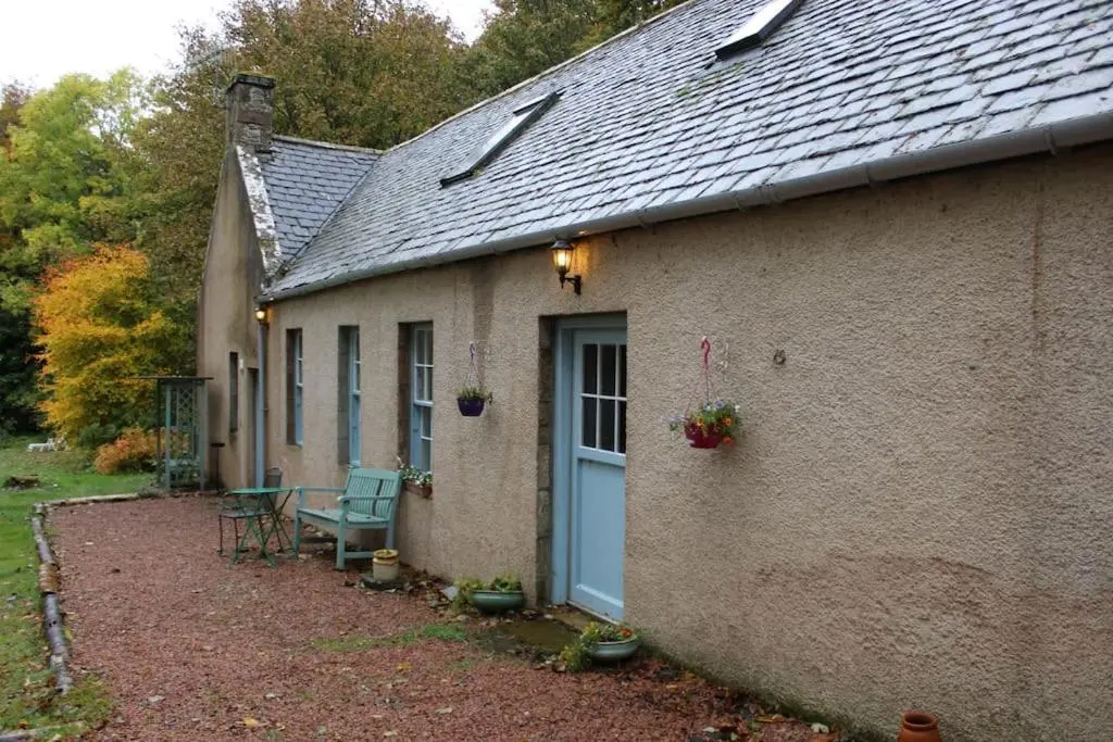 a house with a blue door and a table and chairs at Spacious Cottage in the Grounds of a Scottish Castle in Insch