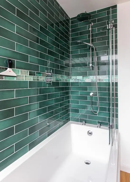 a green tiled bathroom with a tub and a shower at Strathy House in Aviemore