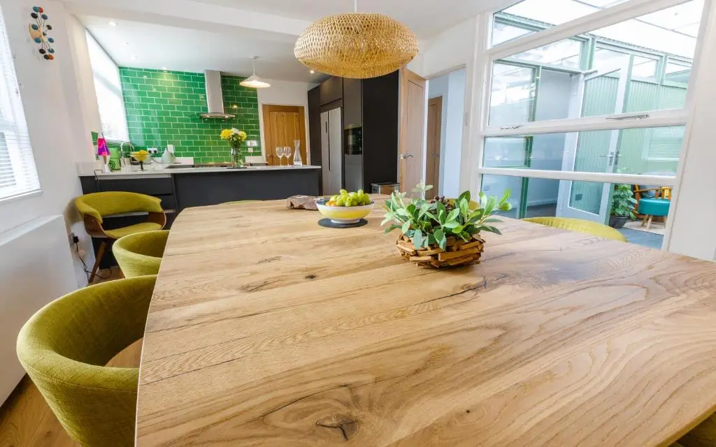 a large wooden table in a kitchen with green chairs at Strathy House in Aviemore