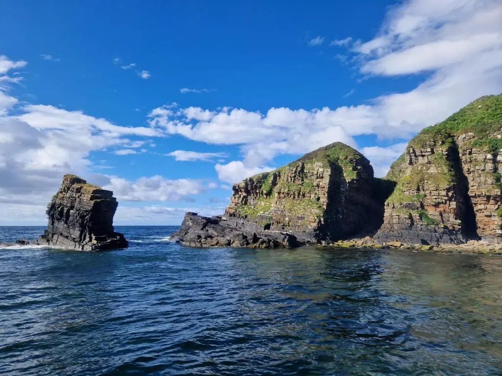 two large rocks in the ocean on a sunny day at Bromach Lodge in Latheron