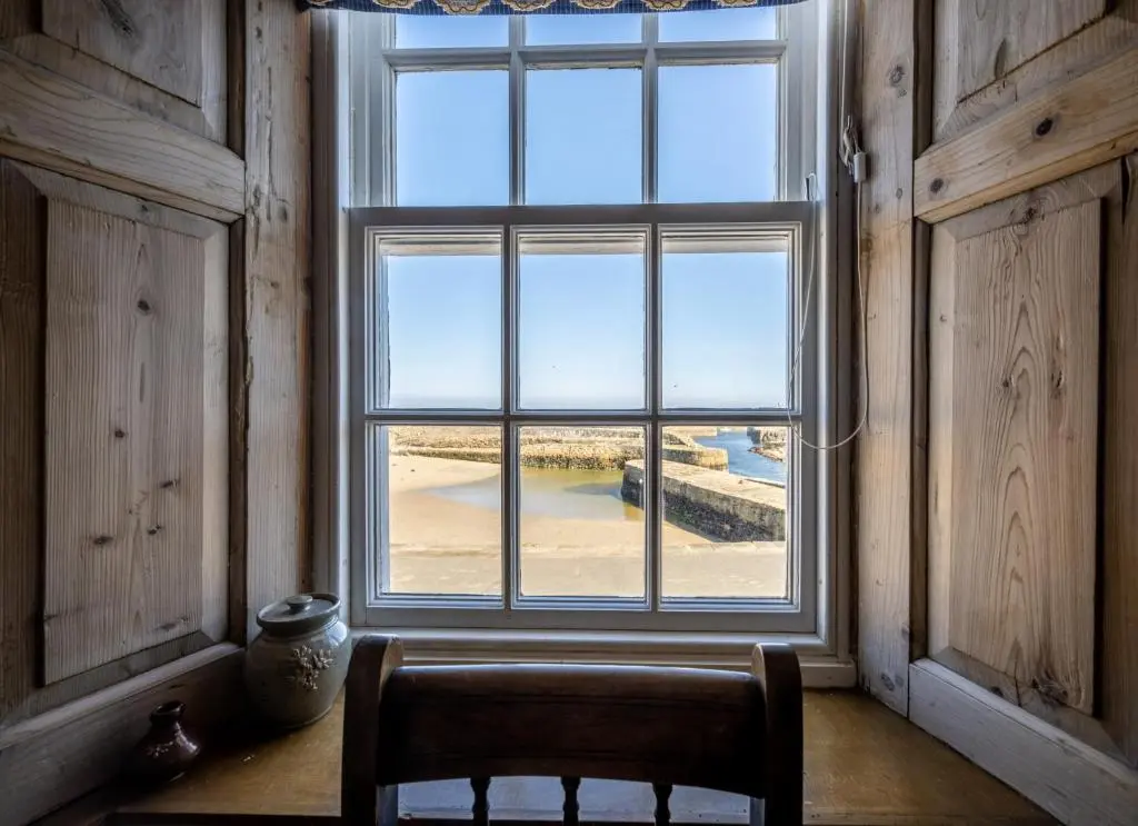 a window in a room with a chair in front of it at 6 Shorehead, Portsoy in Portsoy