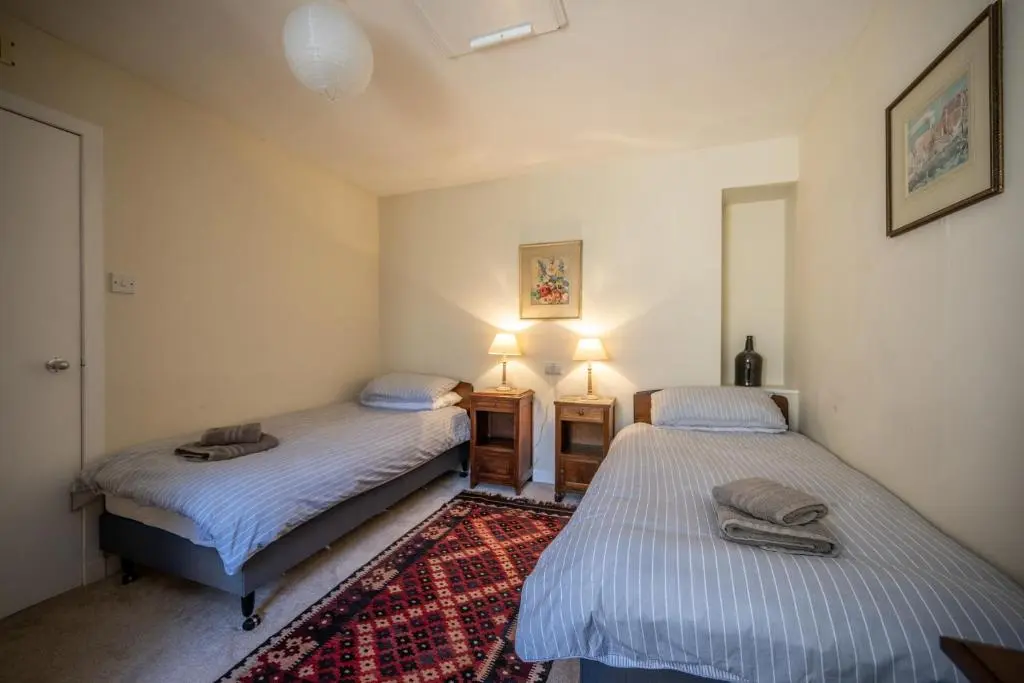 two twin beds in a room with a rug at 6 Shorehead, Portsoy in Portsoy