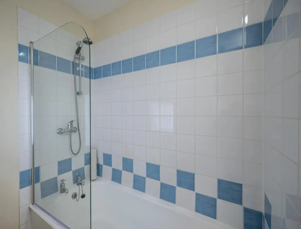 a bathroom with a shower with blue and white tiles at 6 Shorehead, Portsoy in Portsoy
