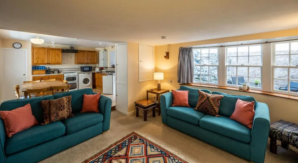 a living room with two blue couches and a kitchen at 6 Shorehead, Portsoy in Portsoy