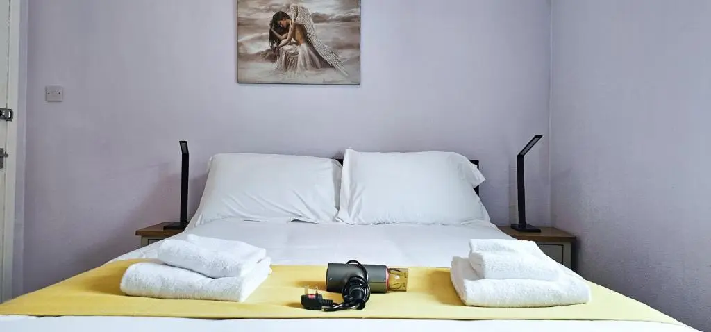a bed with two towels and a camera on it at Cromarty 4 Bedroom Apartment - Inverness in Inverness