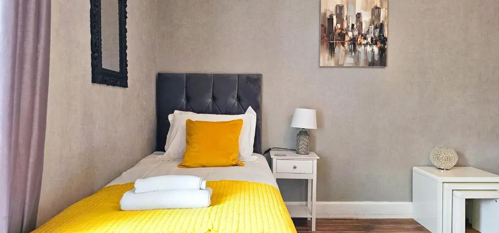 a bedroom with a bed with a yellow blanket at Cromarty 4 Bedroom Apartment - Inverness in Inverness