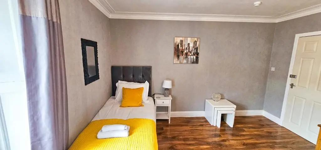 a bedroom with a bed with yellow sheets and yellow pillows at Cromarty 4 Bedroom Apartment - Inverness in Inverness