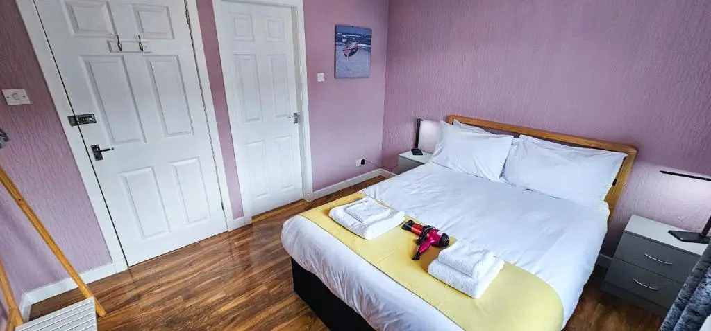 a bedroom with a bed with white sheets and pink walls at Lovat 2 Bedroom Apartment - Inverness in Inverness