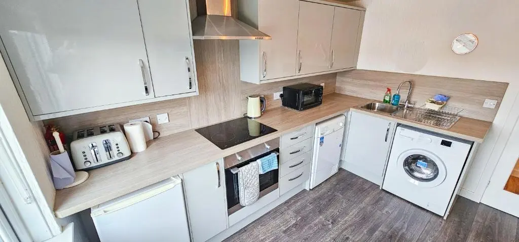 a kitchen with white cabinets and a washer and dryer at Lovat 2 Bedroom Apartment - Inverness in Inverness