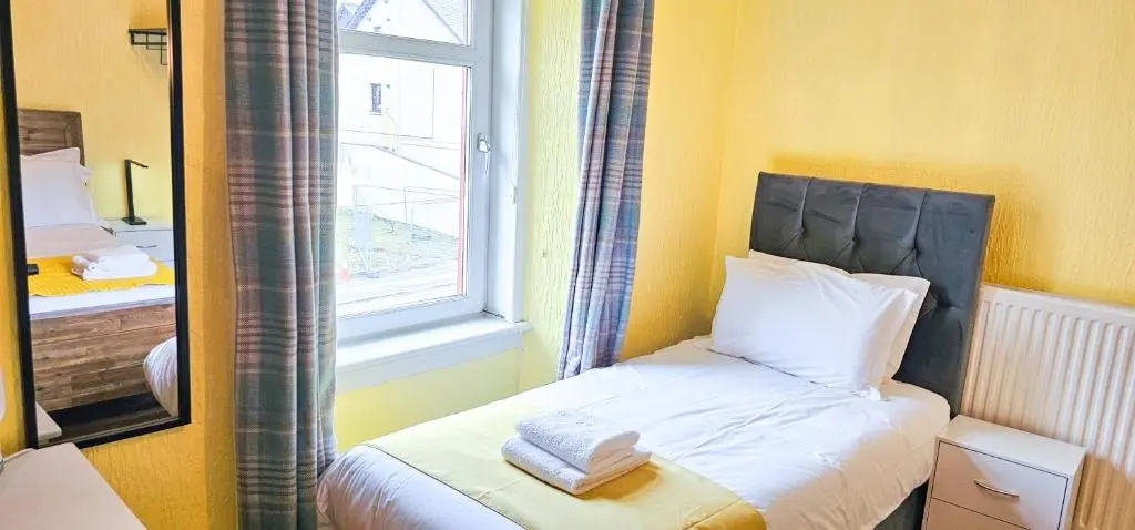 a small bedroom with a bed with a window at Fraser 2 Bedroom Apartment - Inverness in Inverness