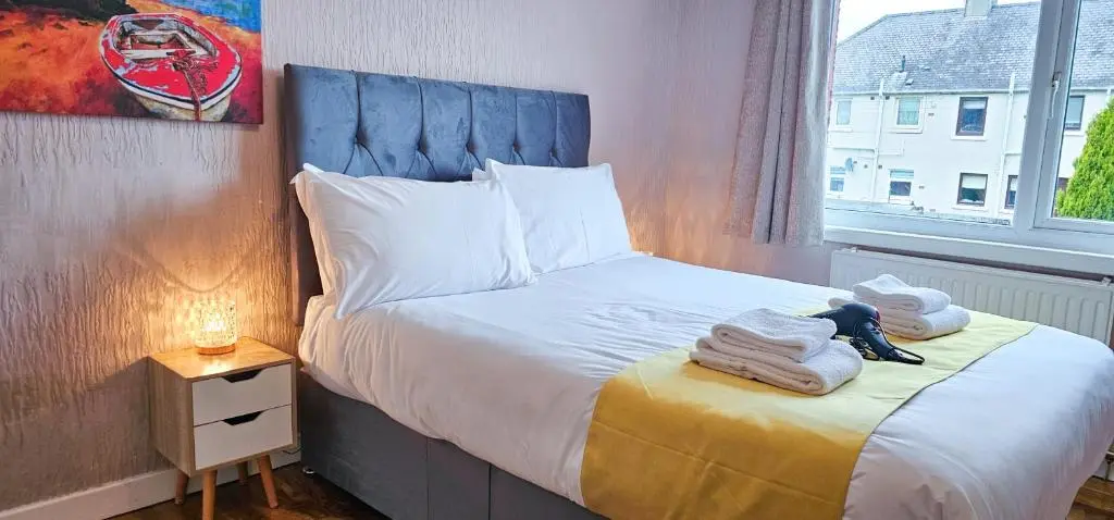 a bedroom with a bed with towels and a window at mySTAYINN Inverness Guest House - Rooms in Inverness