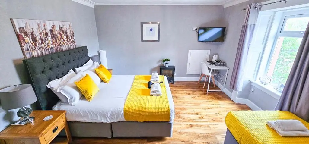a bedroom with a large bed with yellow pillows at mySTAYINN Inverness Guest House - Rooms in Inverness
