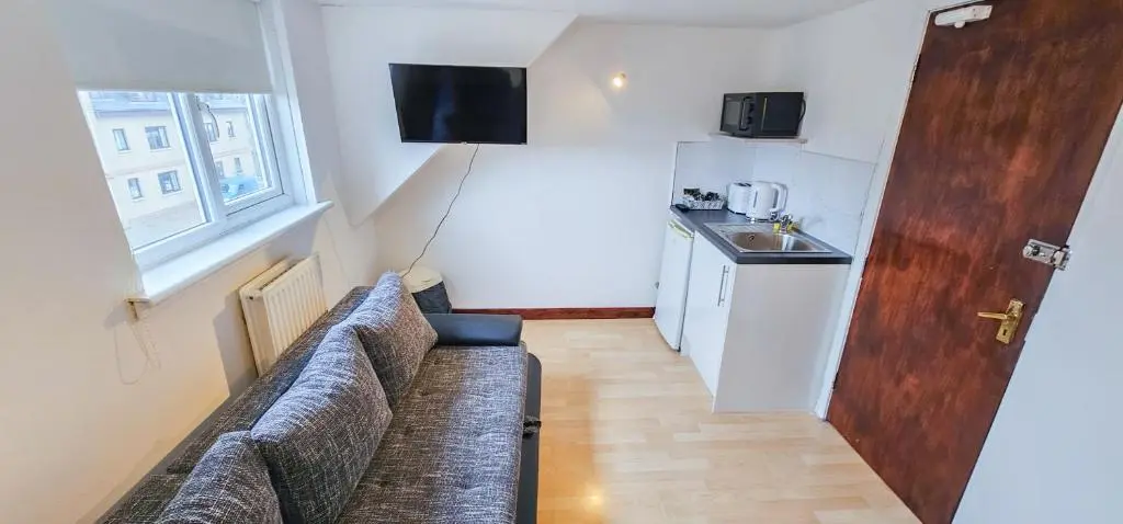 a living room with a couch and a kitchen at mySTAYINN Inverness Guest House - Rooms in Inverness