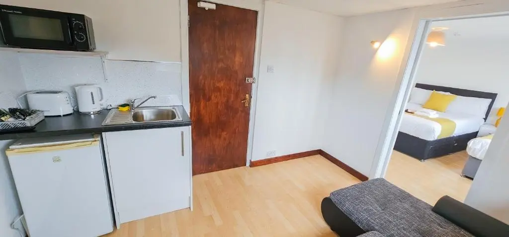 a room with a kitchen and a bedroom with a bed at mySTAYINN Inverness Guest House - Rooms in Inverness