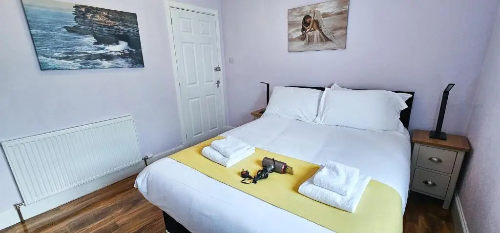 a bedroom with a bed with two towels and two toys on it at mySTAYINN Inverness Guest House - Rooms in Inverness