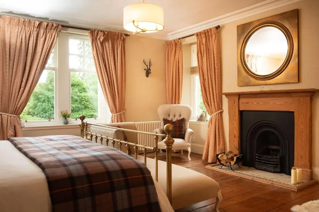 a bedroom with a bed and a fireplace and a mirror at The Dell of Rothiemurchus - Seasgair Lodges in Aviemore