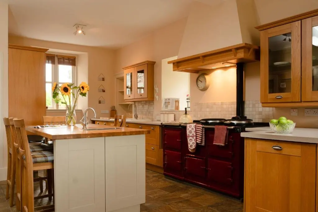 a kitchen with wooden cabinets and a stove top oven at The Dell of Rothiemurchus - Seasgair Lodges in Aviemore