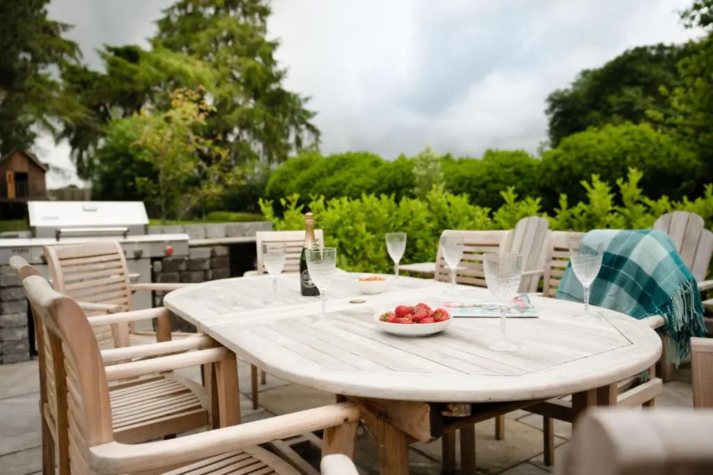 a wooden table with a bowl of fruit and wine glasses at The Dell of Rothiemurchus - Seasgair Lodges in Aviemore