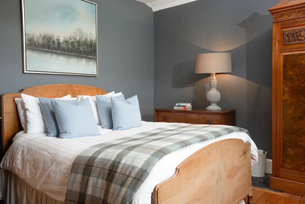 a bedroom with a large bed with blue walls at The Dell of Rothiemurchus - Seasgair Lodges in Aviemore