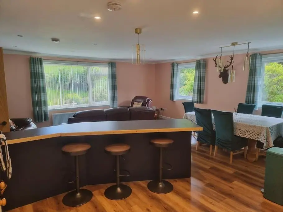 a living room with a bar with chairs and a table at Rowanlea Cottage in Inverness