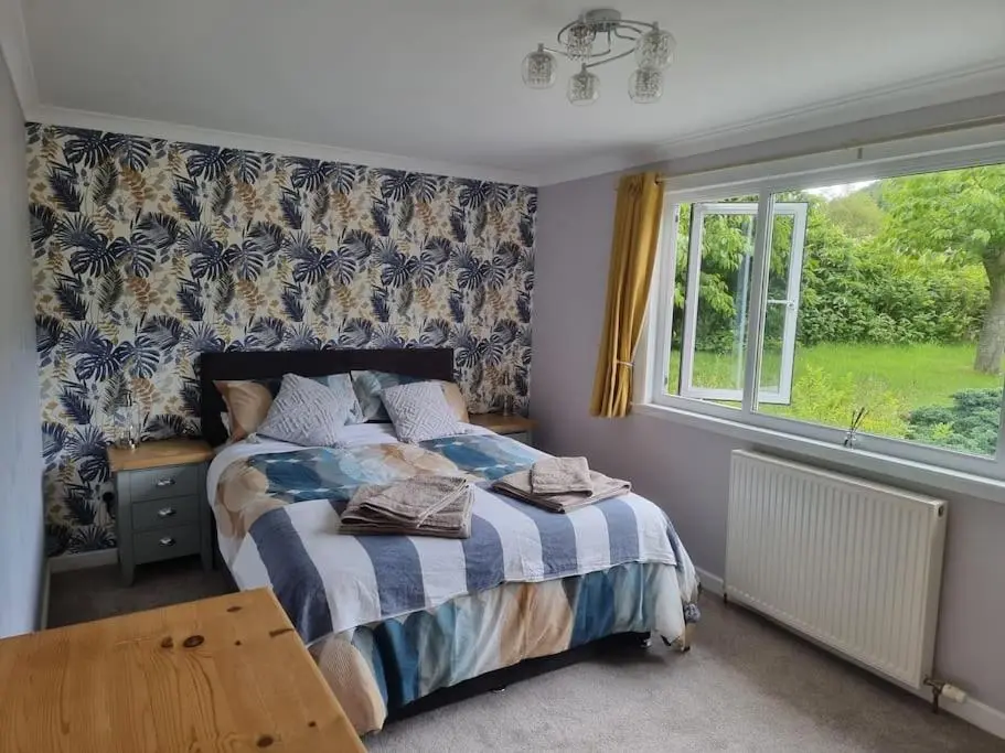 a bedroom with a bed and a window at Rowanlea Cottage in Inverness