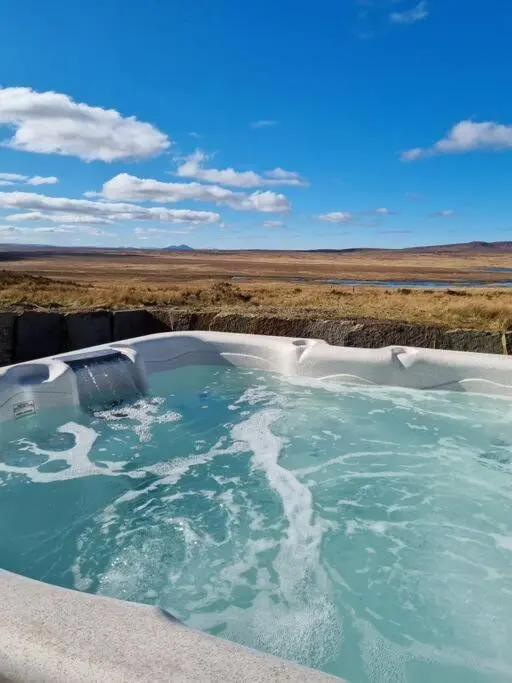 a bath tub filled with water in a field at Torran Cottage - Views, Exclusivity & Tranquility in Halkirk