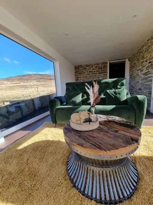 a living room with a green couch and a table at Torran Cottage - Views, Exclusivity & Tranquility in Halkirk