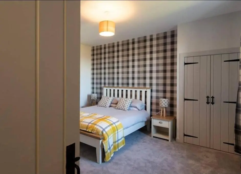 a bedroom with a bed and a checkerboard wall at Torran Cottage - Views, Exclusivity & Tranquility in Halkirk