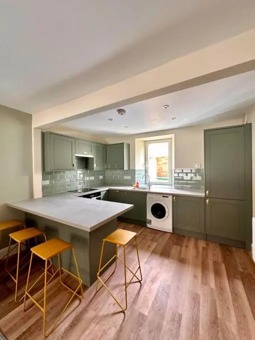 a kitchen with green cabinets and a large island at Warm and Cosy City Centre House in Inverness