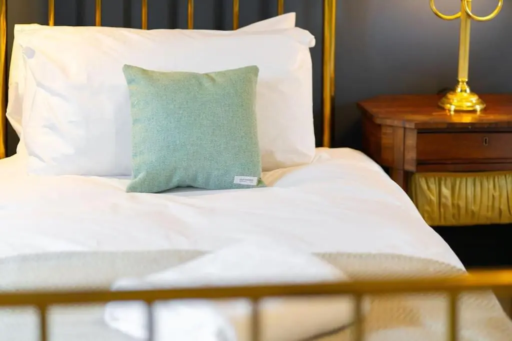 a white bed with a green pillow on it at Westerpark Cottage, Pet & Family Friendly Countryside Retreat, Aberdeenshire in Huntly