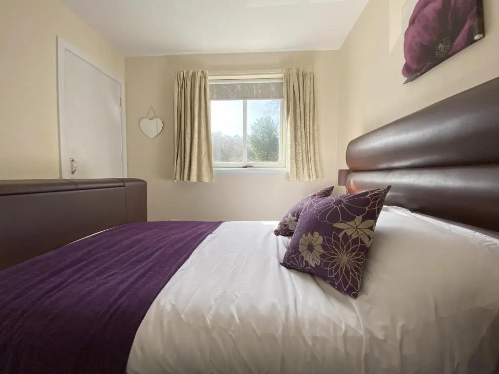 a bedroom with a bed with purple sheets and a window at Treetops - Bright 2 Bed Flat - Super Location in Inverness