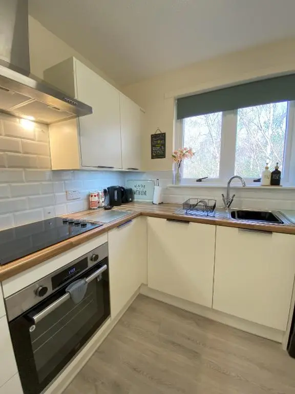 a kitchen with white cabinets and a sink and a window at Treetops - Bright 2 Bed Flat - Super Location in Inverness