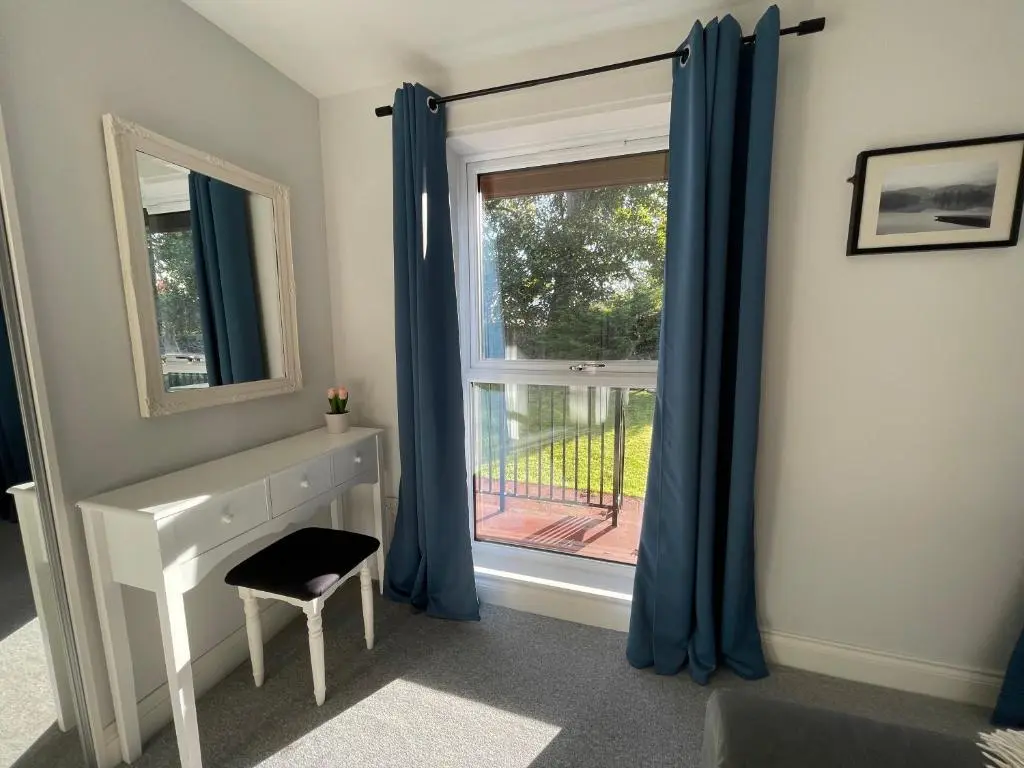 a room with a window with blue curtains and a desk at Modern Coastal Retreat, 5-Bedroom, 4-Bathroom Home, with Parking in Portsoy in Portsoy