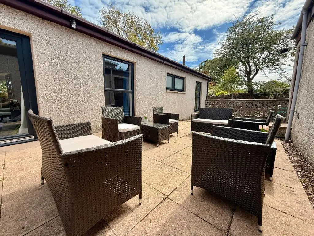 an outdoor patio with chairs and tables and chairs at Modern Coastal Retreat, 5-Bedroom, 4-Bathroom Home, with Parking in Portsoy in Portsoy