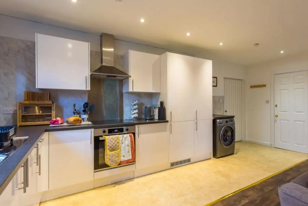 a kitchen with white cabinets and a stove top oven at The Bungalow - Ardullie Lodge in Dingwall