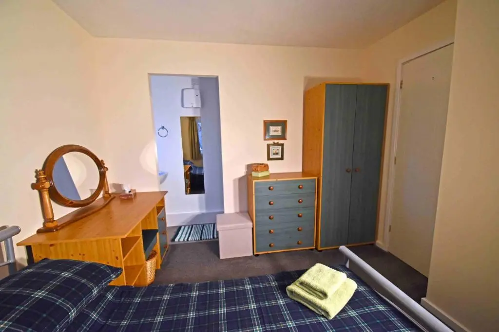 a bedroom with a bed and a dresser and a mirror at Birch View in Aviemore