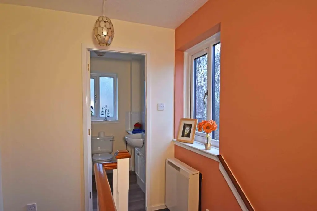 an orange bathroom with a toilet and a window at Birch View in Aviemore