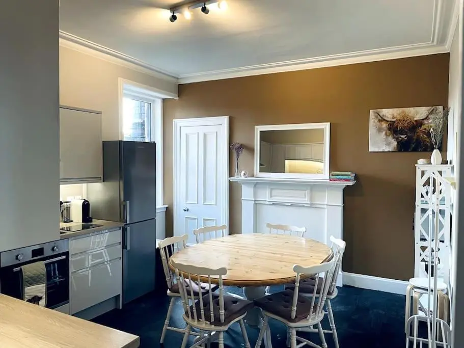 a kitchen with a table and chairs in a room at Charming 3-bedroom maisonnette in Inverness City Centre in Inverness
