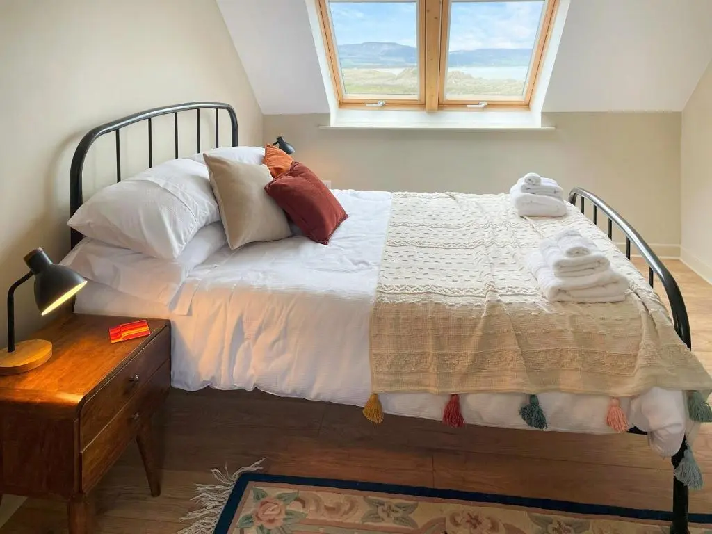 a bedroom with a bed with pillows and a window at The Wee Belter in Dornoch