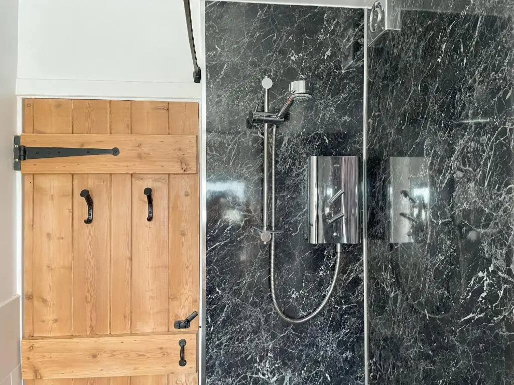 a bathroom with a shower and a wooden cabinet at The Wee Belter in Dornoch