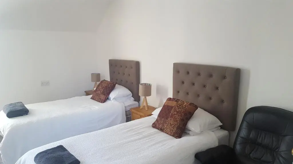 a room with two beds and a chair in it at Riverside Apartments in Wick