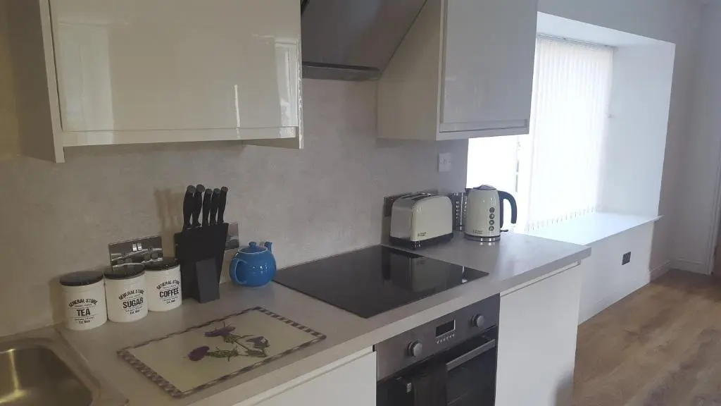 a kitchen with white cabinets and a counter top at Riverside Apartments in Wick