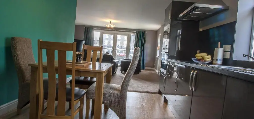 a kitchen with a table and a dining room at Riverside Apartments in Wick