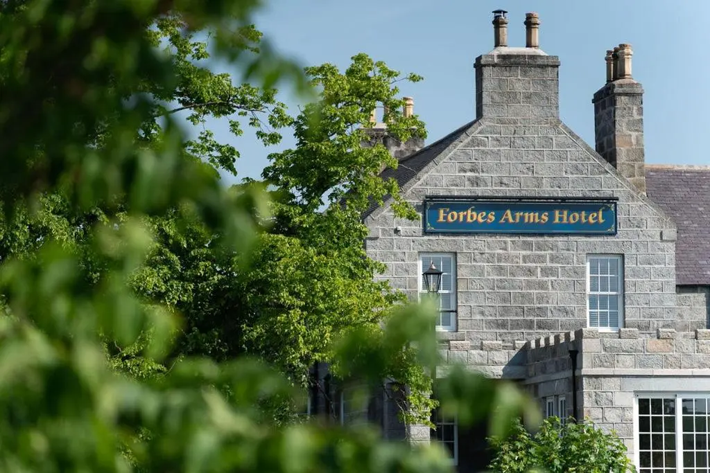 a stone building with a blue sign on it at The Forbes Arms Hotel in Alford