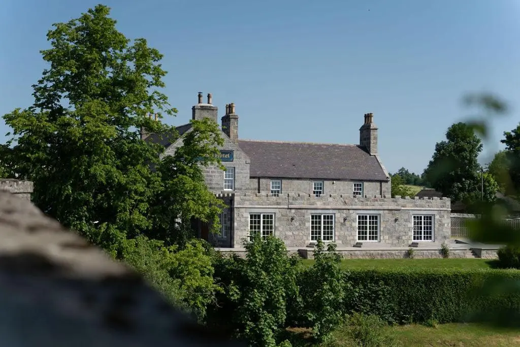 an old stone house with two chimneys at The Forbes Arms Hotel in Alford